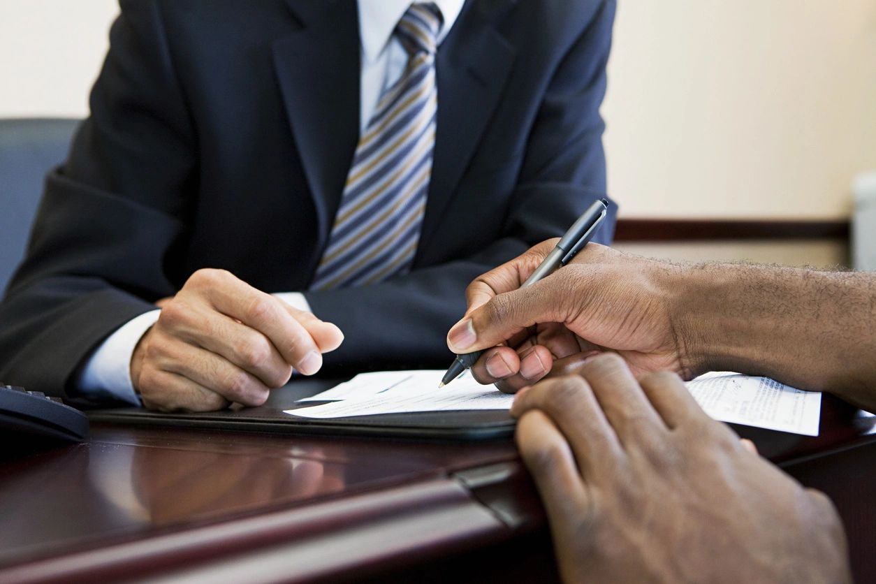 A man in a suit is writing on paper.