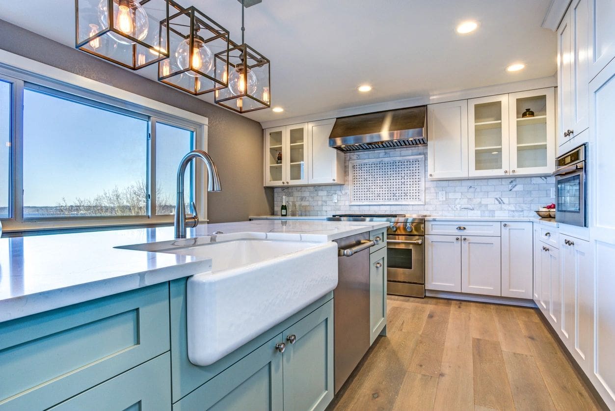 A kitchen with white cabinets and blue island.